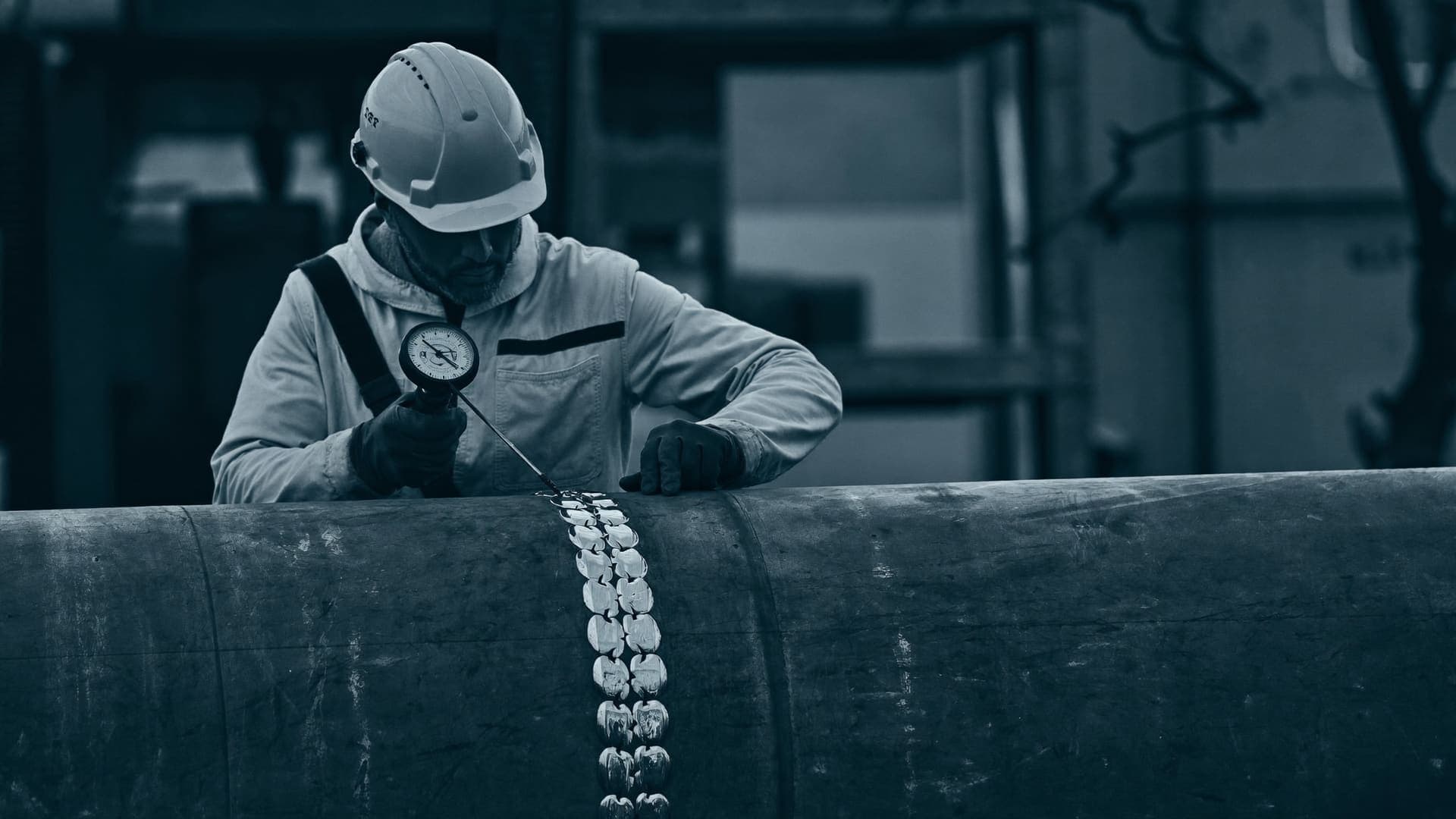 Quality inspector examining a weld seam on large-diameter steel pipe